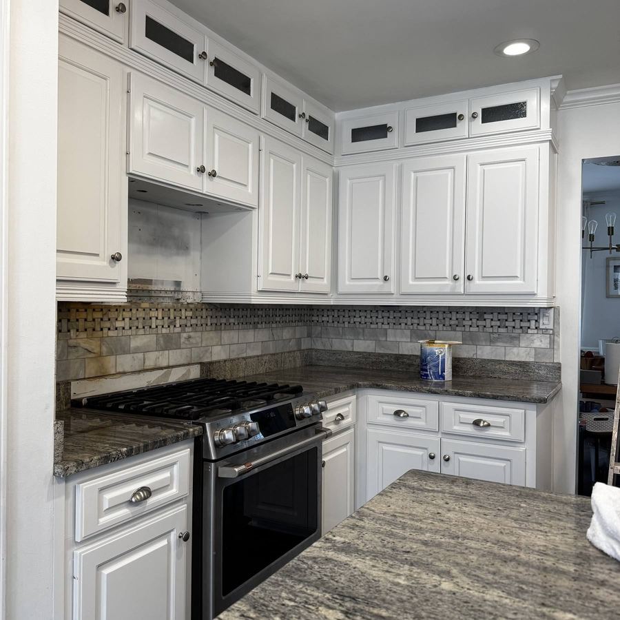 Kitchen cabinets painted white with a tile backsplash and dark counters