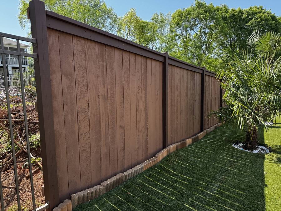 Two-tone privacy fence with dark posts and rails framing lighter boards