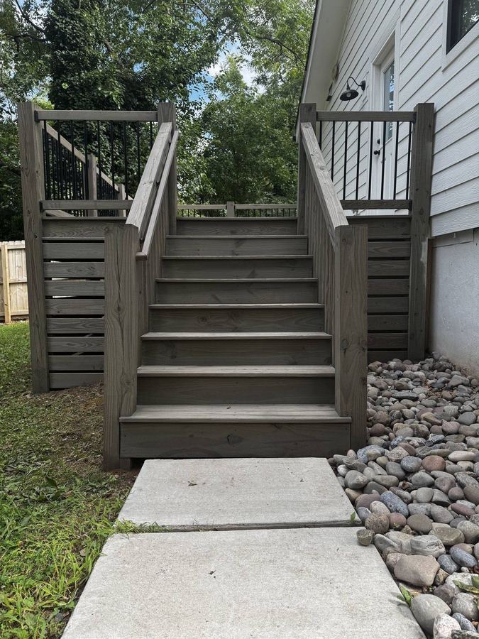 Grey stained deck stairs beside a rock bed
