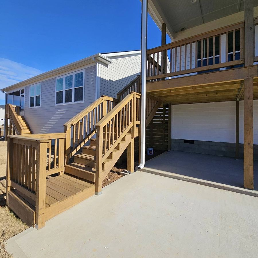 New deck stairs and rails leading to a back door, stained a light tone