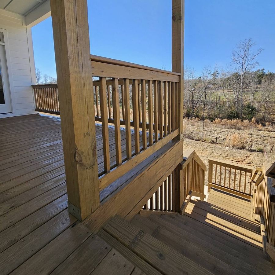 Stained deck rails and boards looking out over a field