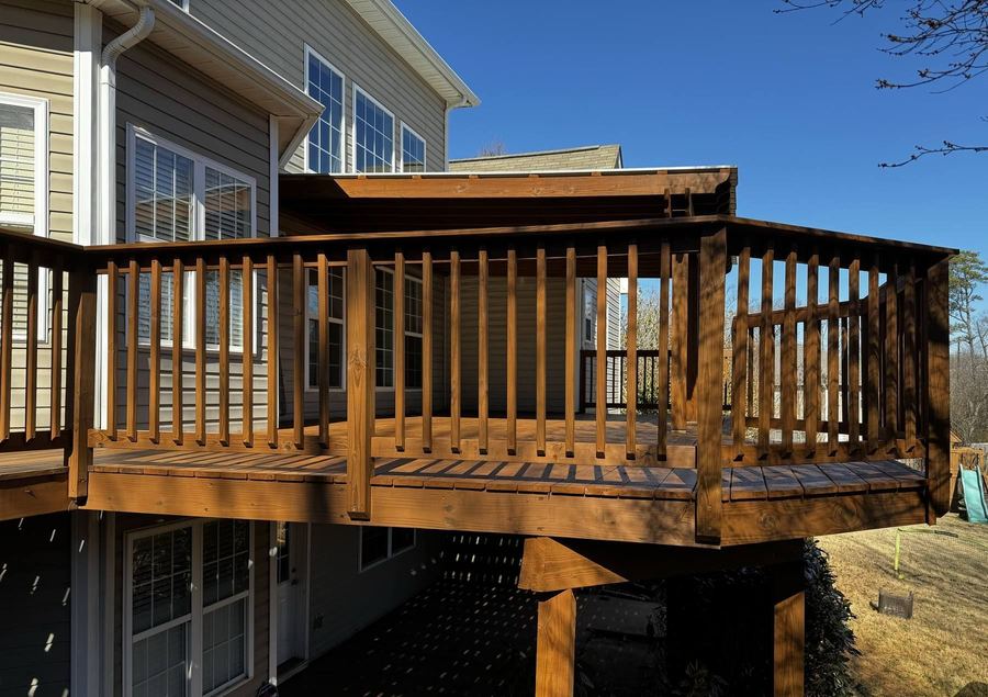 Second-story deck with rails stained a warm tone in full sun