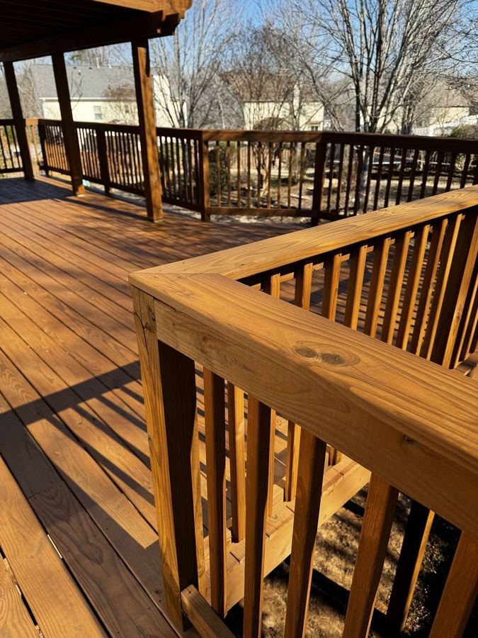 Stained deck rail corner with the grain showing in the sun and a second deck beyond