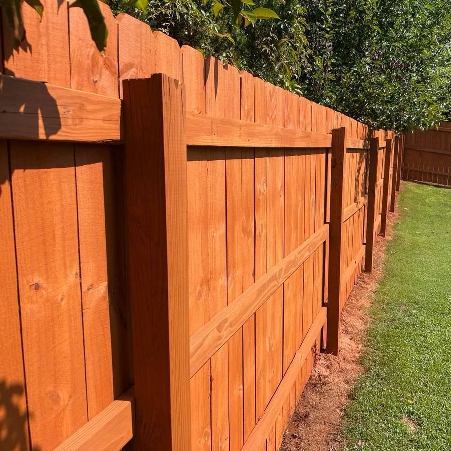 Close view of stained fence boards and a post in afternoon sun