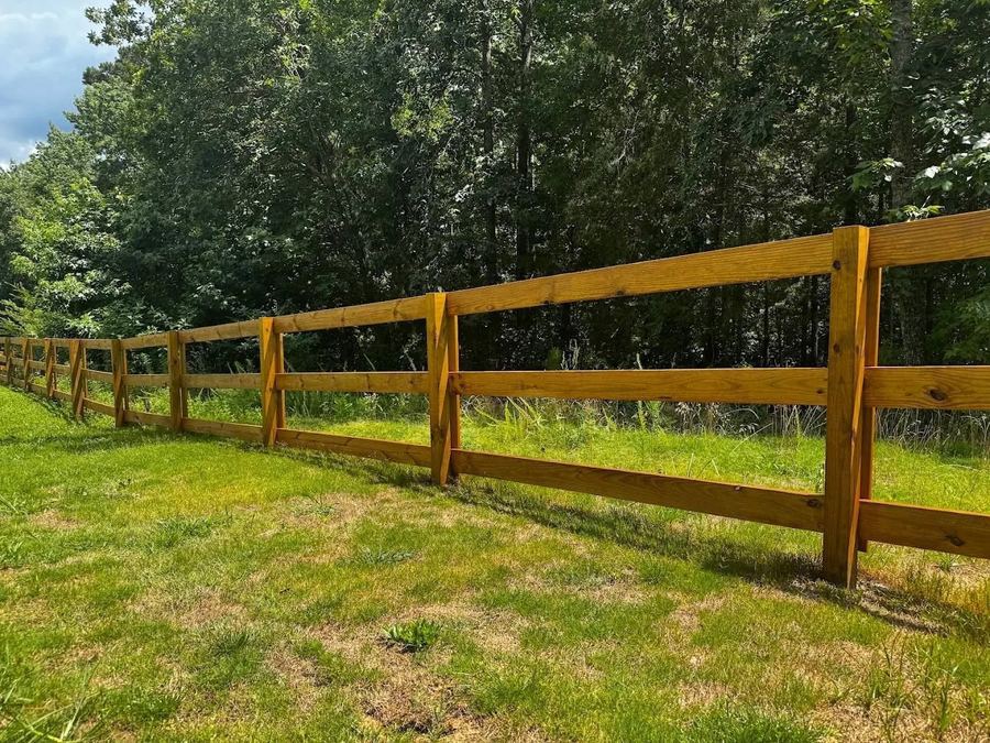 Farm rail fence with a light transparent stain across a green pasture