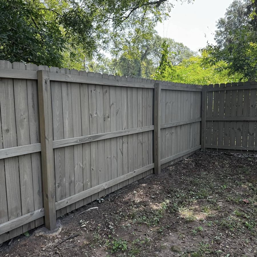 Grey stained privacy fence corner showing interior rails and dog-ear pickets