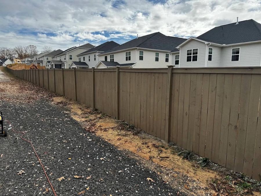 Long HOA perimeter fence stained one color along a row of new homes