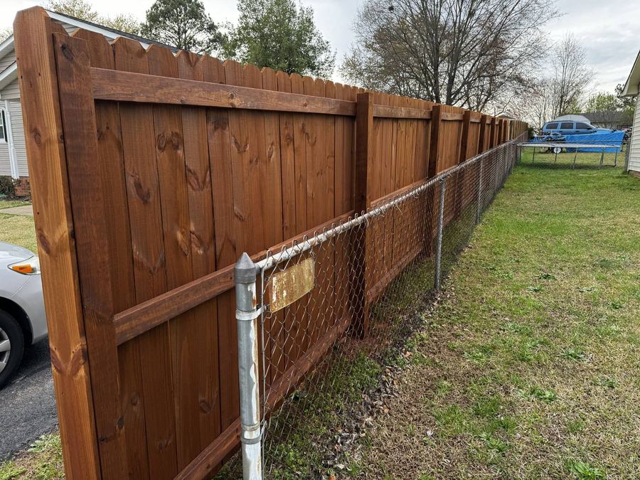 Stained privacy fence running tight against a chain-link fence