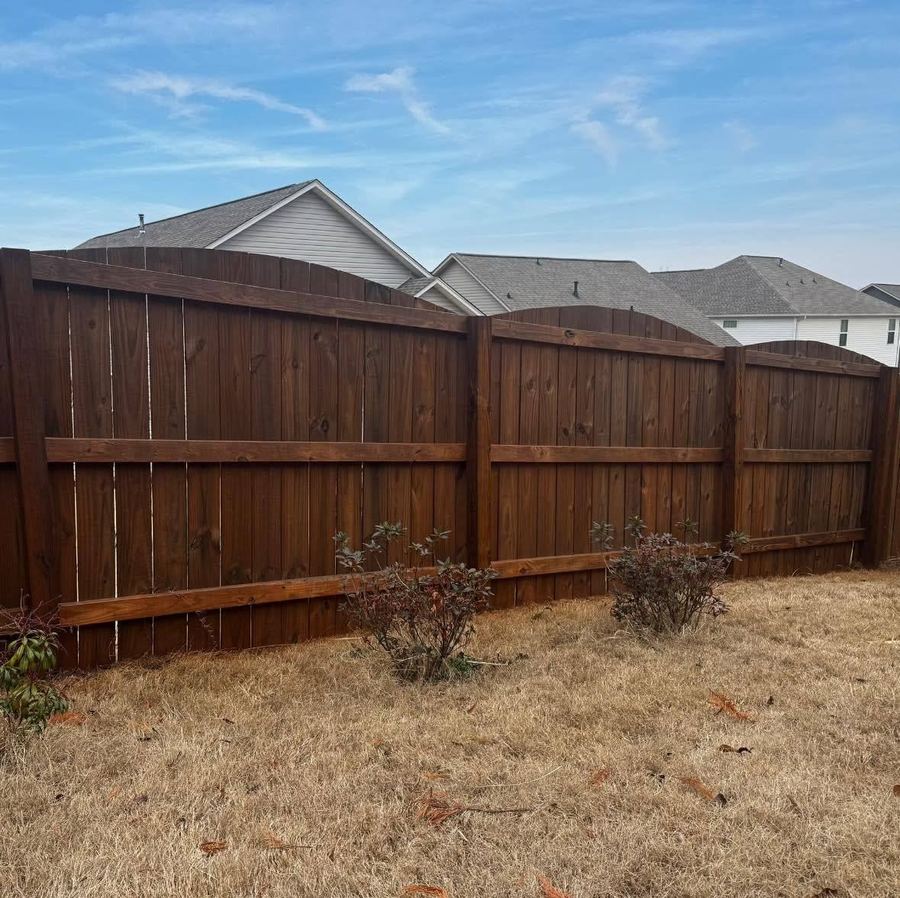 Privacy fence with arched panel tops, freshly stained