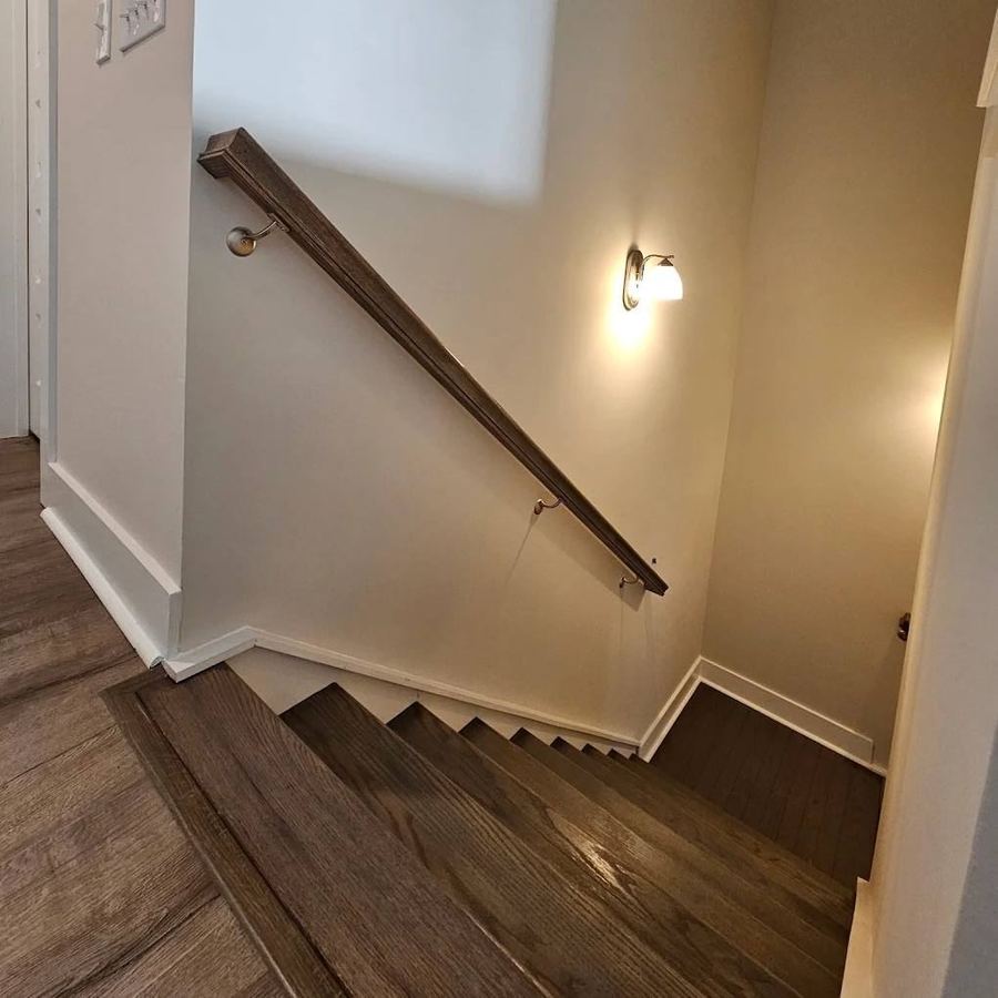 Interior staircase with stained wood steps and a dark handrail