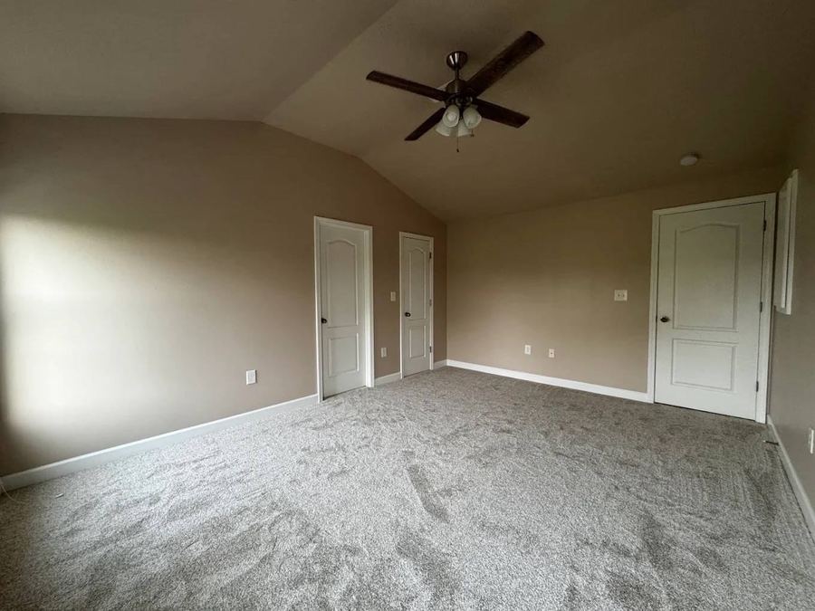 Freshly painted primary bedroom with vaulted ceiling and carpet