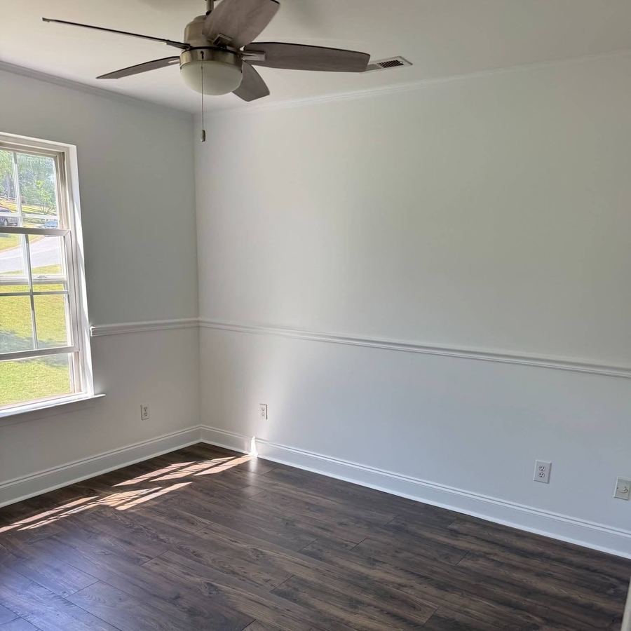 Painted bedroom corner with window trim and wood floors