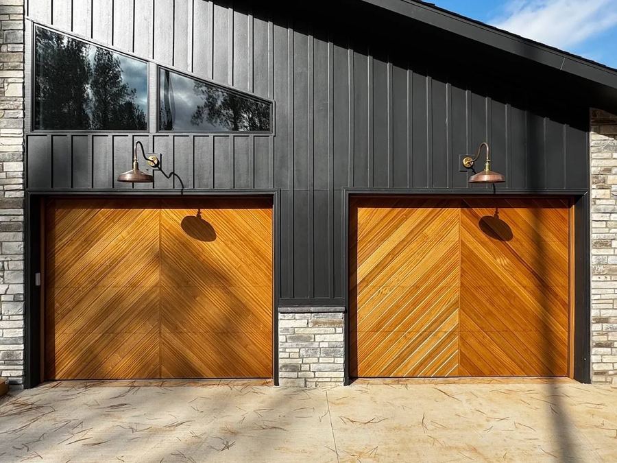 Two wood garage doors with a clear polyurethane finish on a dark modern home