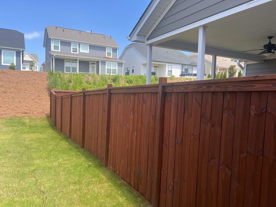 Long stained privacy fence stepping down a slope in a newer subdivision