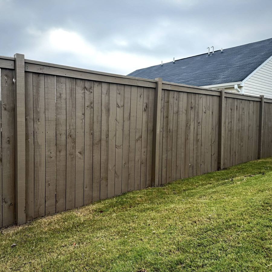 Privacy fence with a grey-brown semi-solid stain beside a house