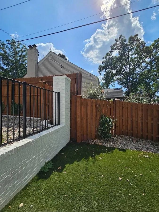 Stained shadowbox fence meeting a white masonry pillar beside a lawn