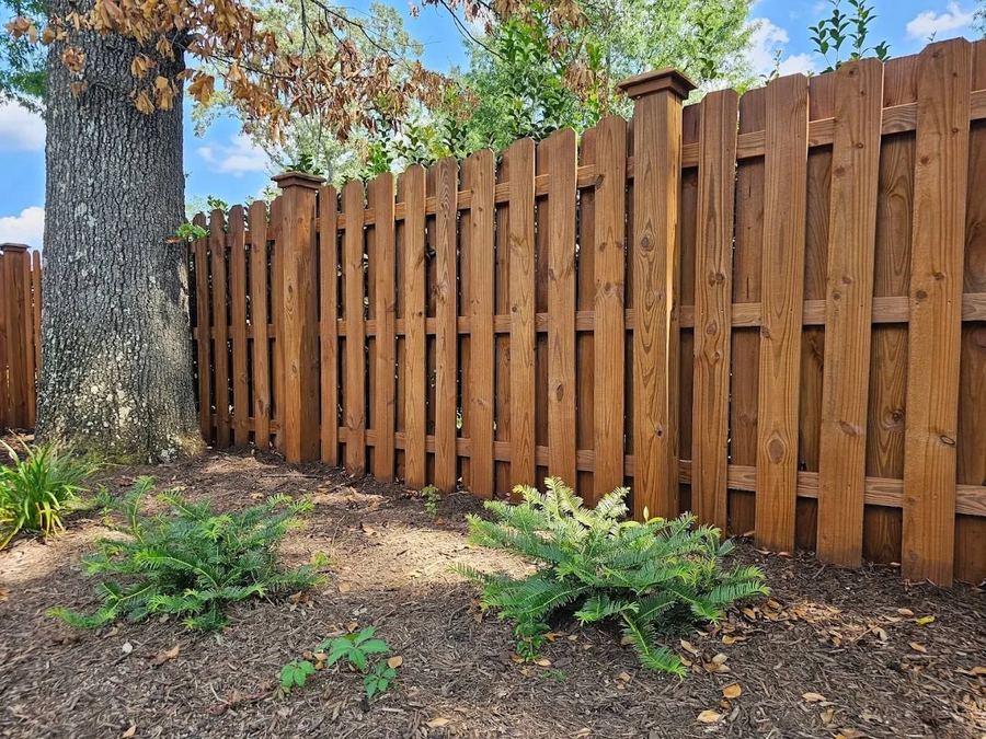 Close view of a stained shadowbox fence and post caps