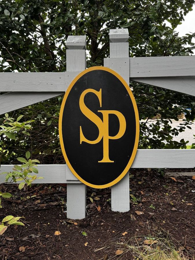 Neighborhood entrance sign with a painted logo on a stained post