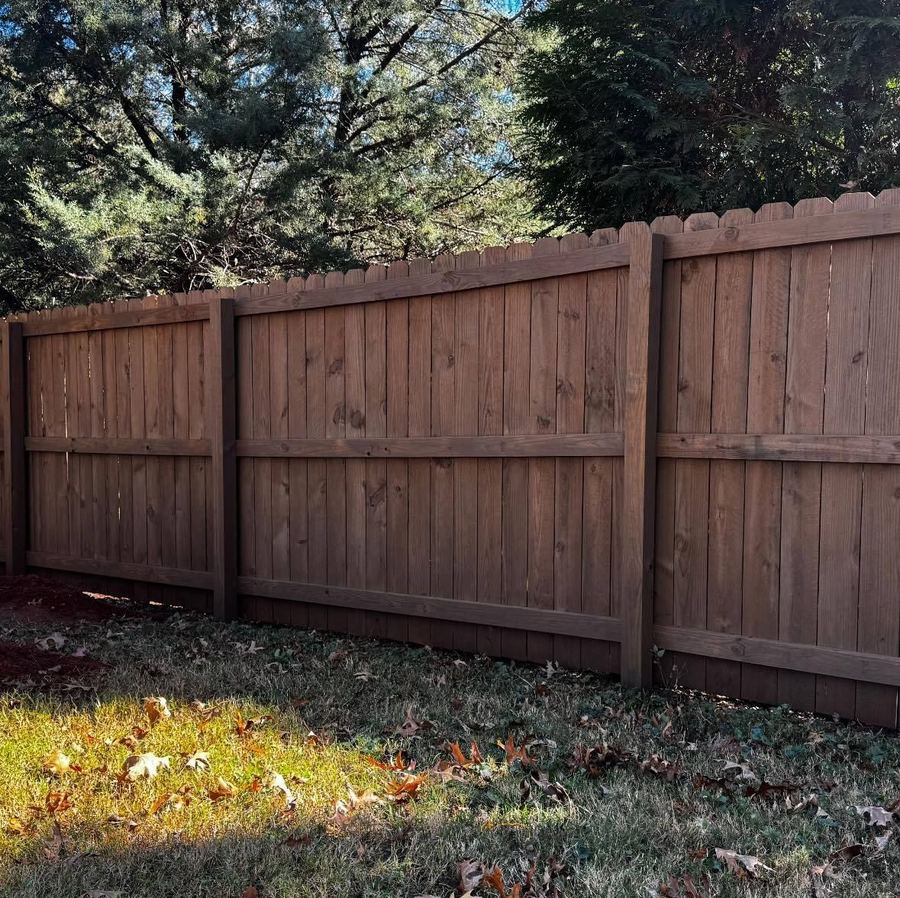 Standard dog-ear privacy fence with a fresh stain along a lawn