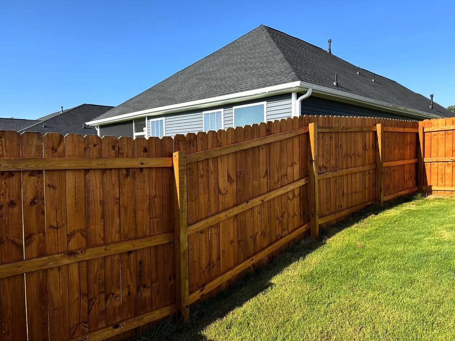 Privacy fence with a warm transparent stain and a house behind it